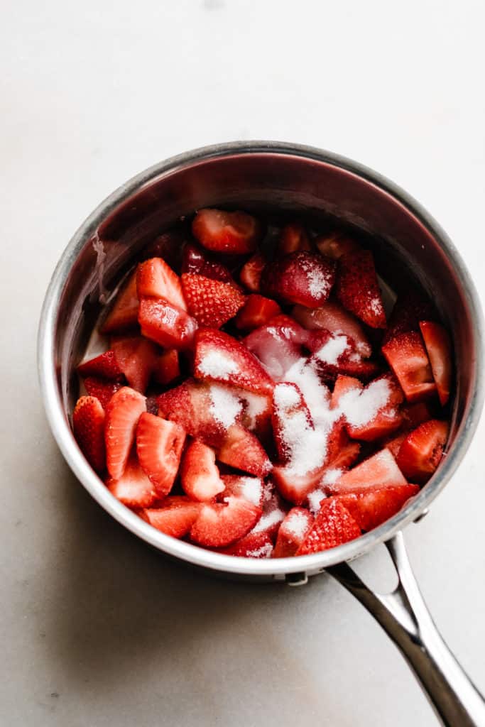 A pot with strawberries and sugar. 