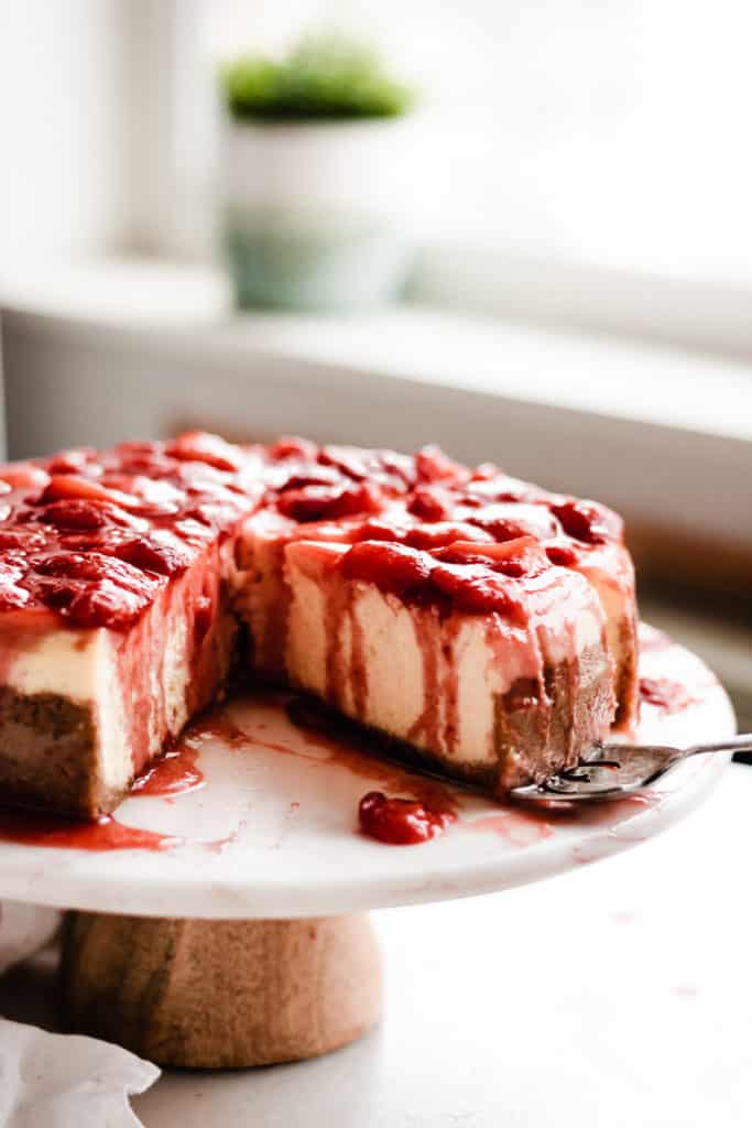 Close-up of side of a slice of cheesecake with strawberry sauce.