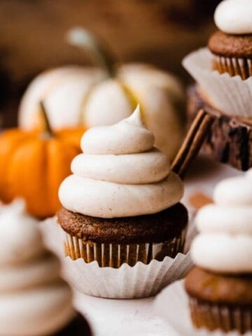 A close-up of a pumpkin cupcake topped with a swirl of brown butter frosting.