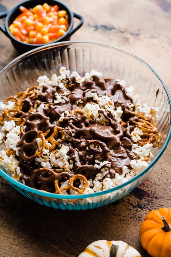 A bowl of popcorn, pretzels, and chex covered in melted chocolate