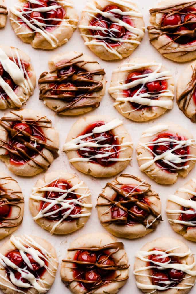 Cherry Pie Cookies drizzled with white and milk chocolate on a light pink surface