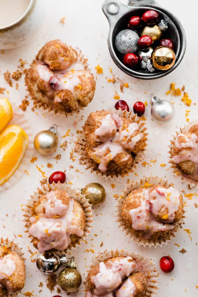 Monkey Bread Muffins topped with a pink glaze, with mini ornaments and fresh cranberries scattered around