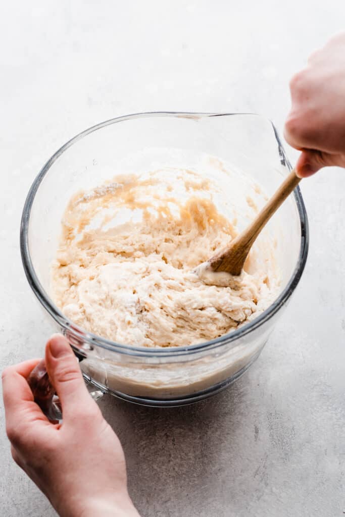 A hand stirring the beer bread batter in a mixing bowl