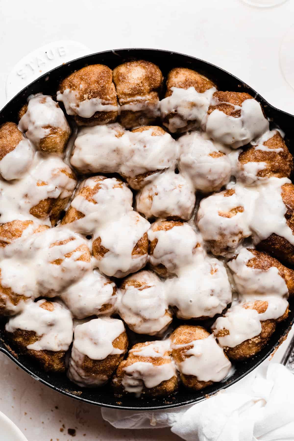 A skillet of baked pieces of cinnamon sugared dough topped with a glaze