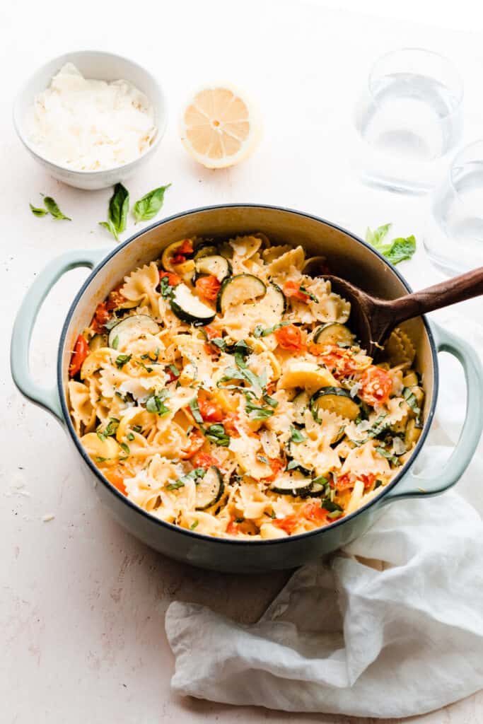 A pot of pasta with zucchini, tomatoes, and fresh basil