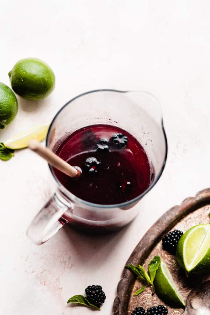 A pitcher of muddled blackberries with limeade and brandy