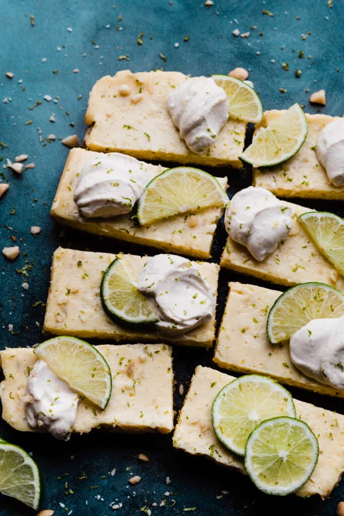 Key Lime Pie Bars topped with whipped cream, lime slices and zest.