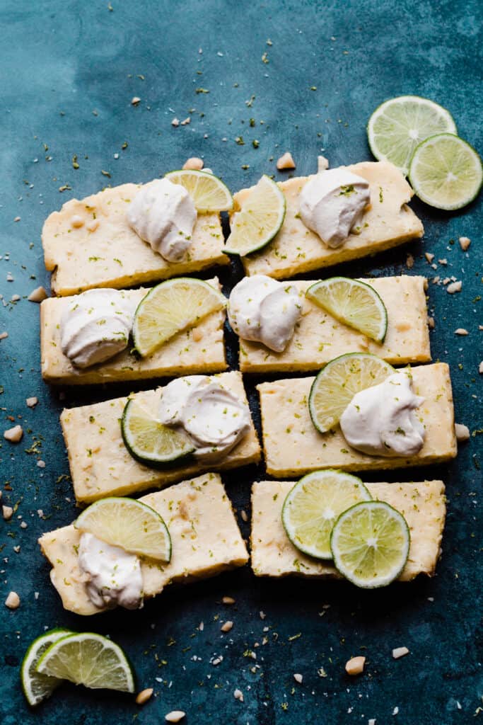 Key Lime Pie Bars topped with whipped cream, lime slices, and lime zest.