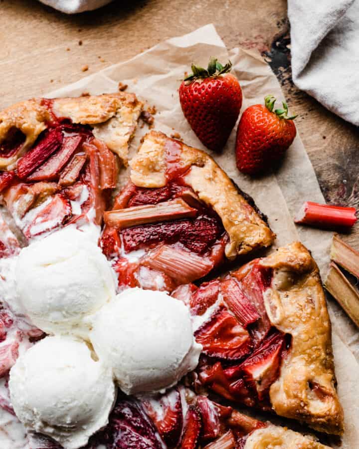 A close-up of the sliced strawberry rhubarb galette, topped with vanilla ice cream.