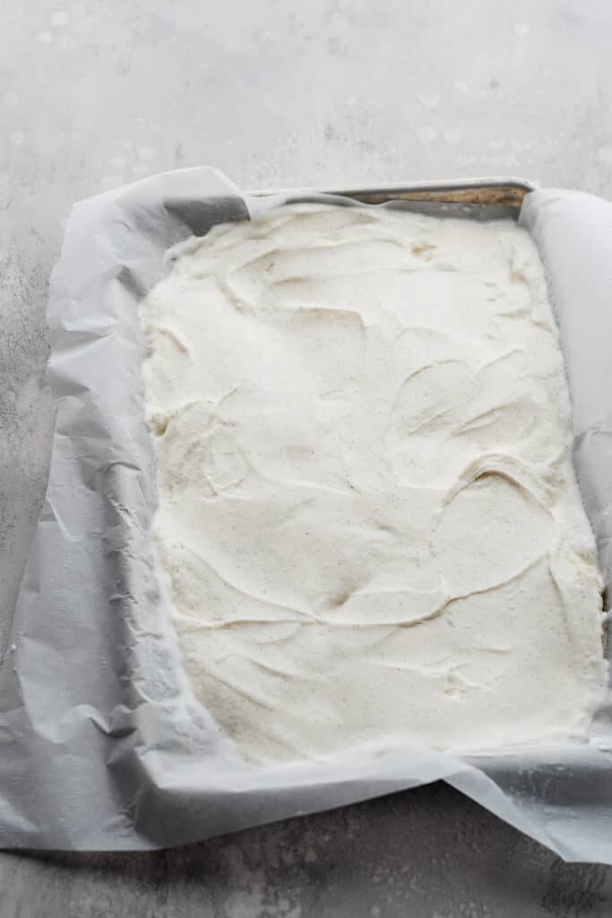A sheet pan lined with parchment and filled with vanilla ice cream.
