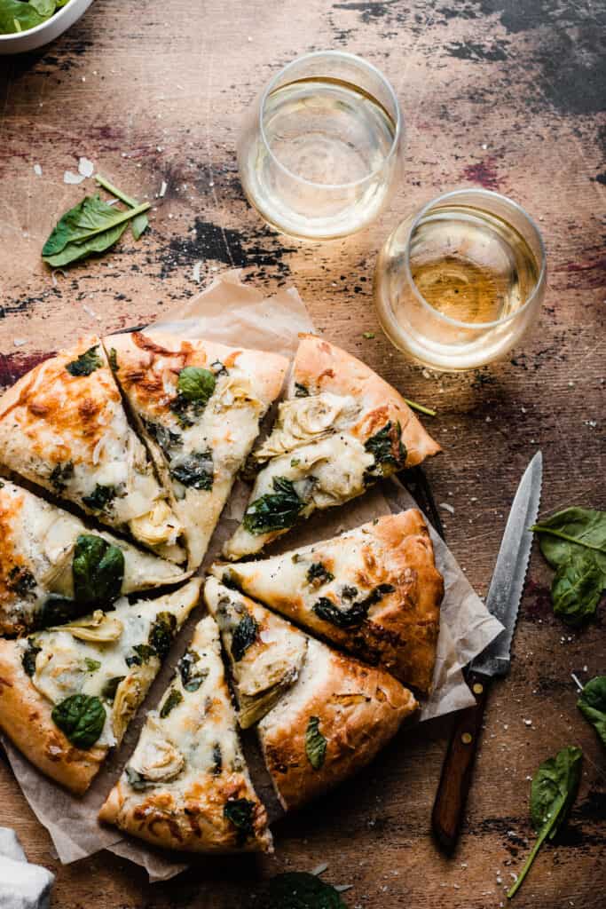 The sliced spinach artichoke pizza on a wooden surface