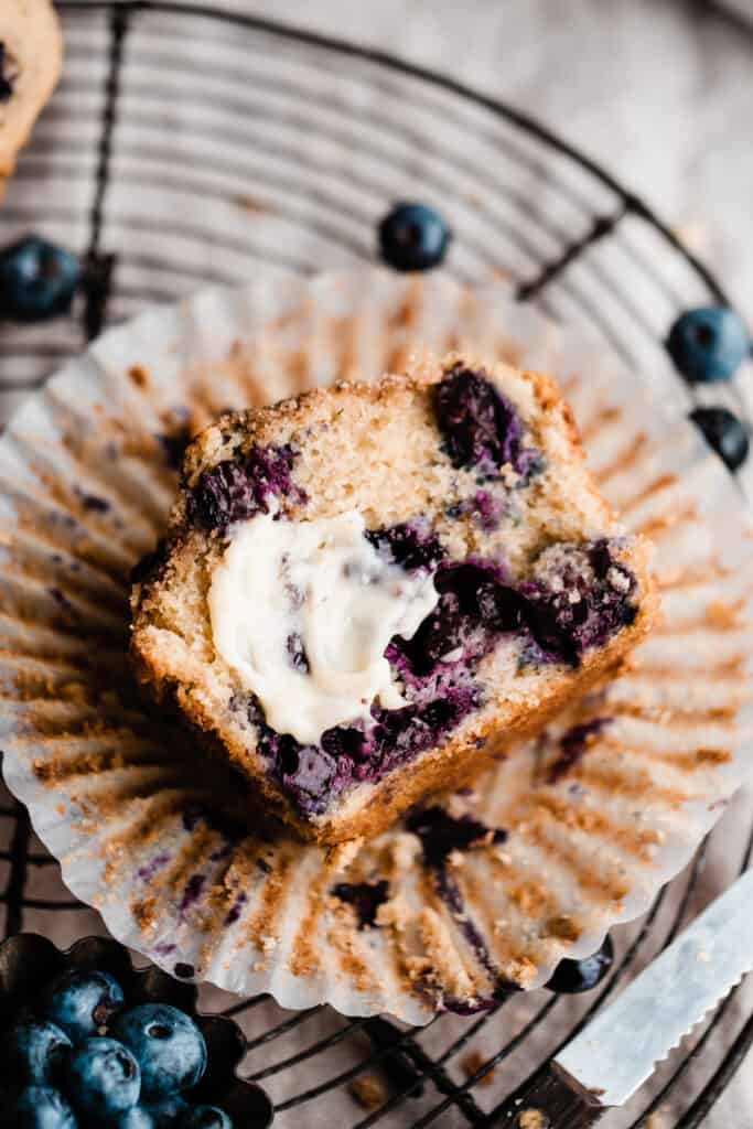 A close-up of half a blueberry muffin, slathered in butter.