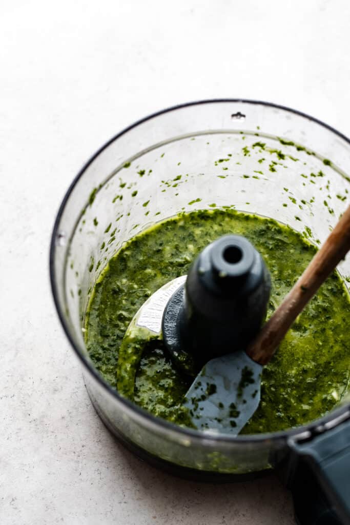 A food processor with the blended green dressing.