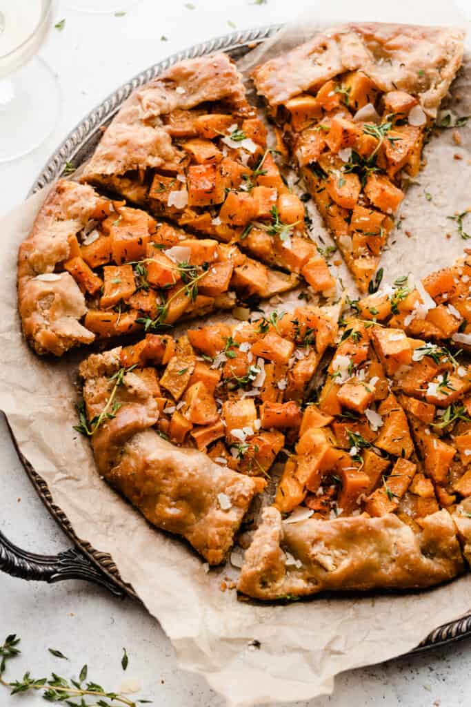 Sliced butternut squash galette on a pan, with flaky homemade pie crust.