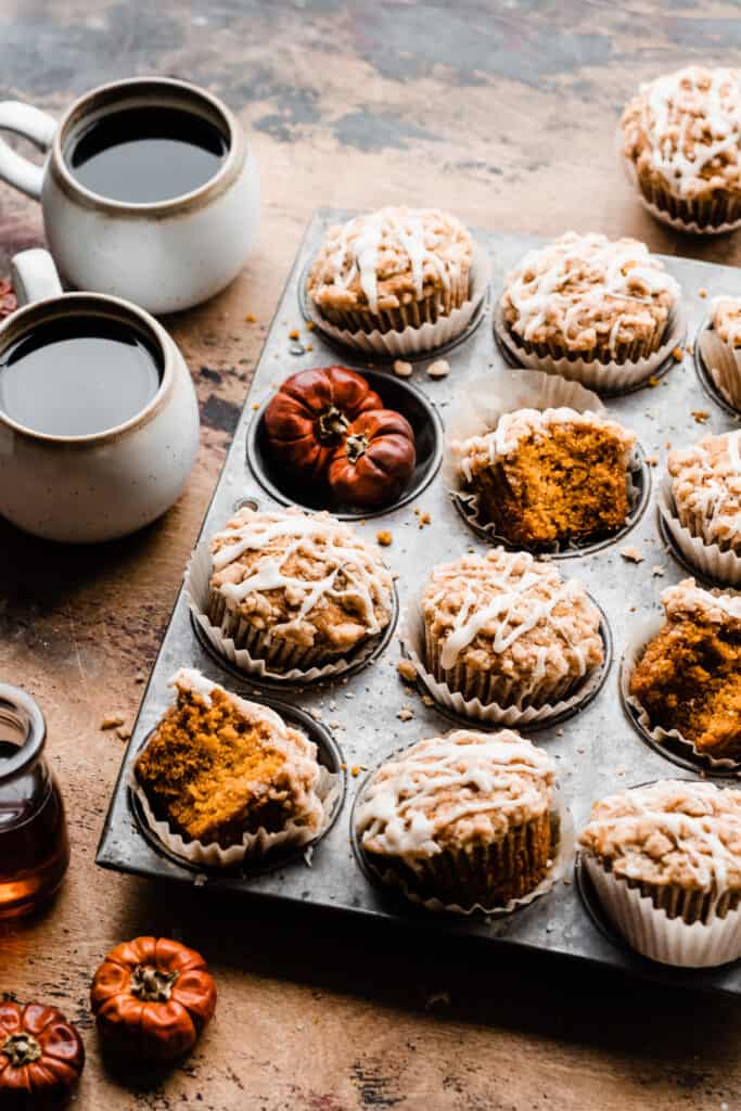 A pan of maple glazed pumpkin streusel muffins on a wood surface.