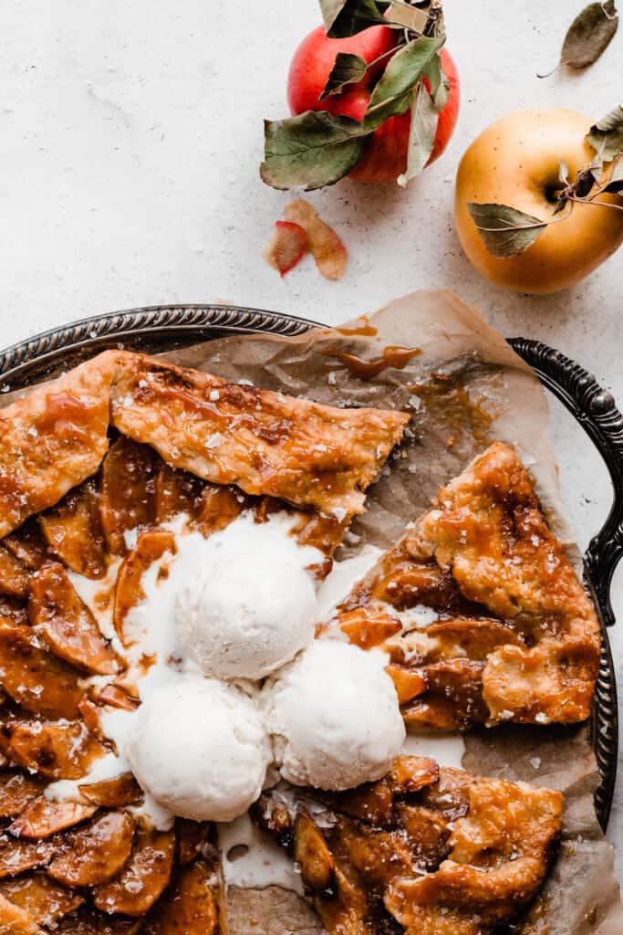 Slices of the caramel apple galette on a tray topped with ice cream.