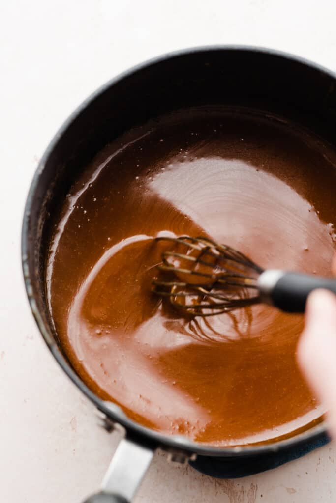 A whisk stirring the finished caramel sauce.