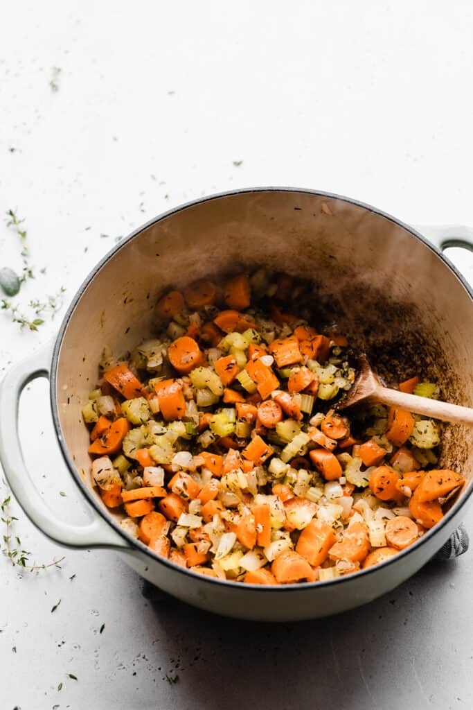 Carrots, celery, and onion being sautéed in a dutch oven.