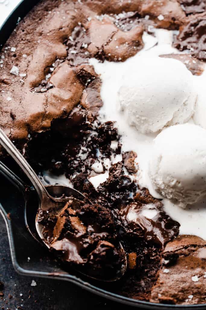 A close-up of two spoons taking a scoop out of the gooey brownie. 
