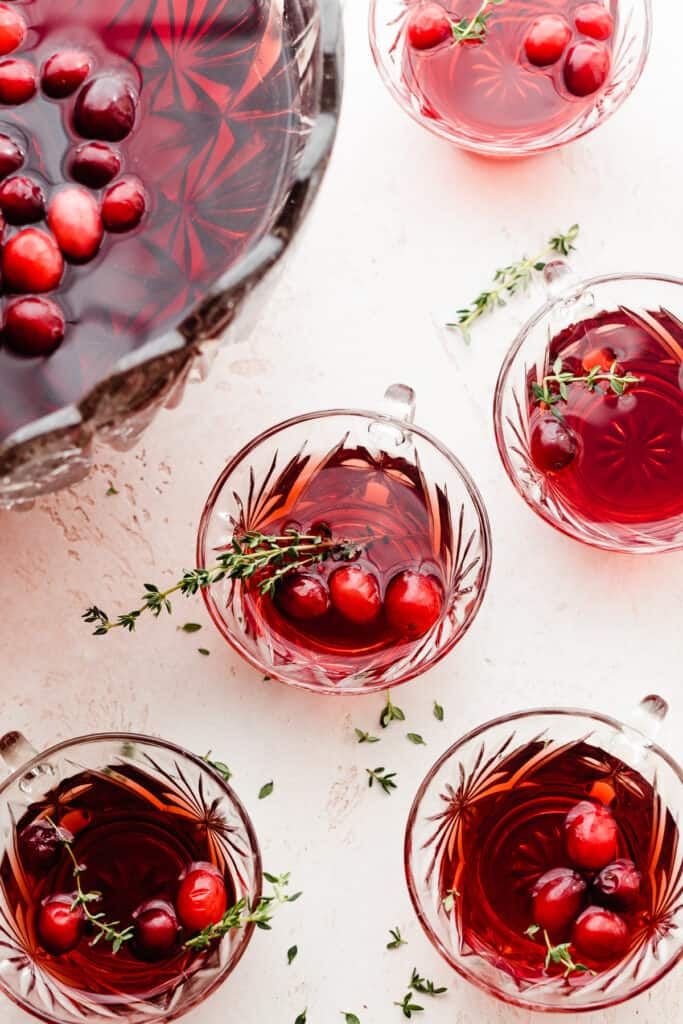 A bird's eye view of punch glasses filled with cranberry punch, with the bowl in the background.
