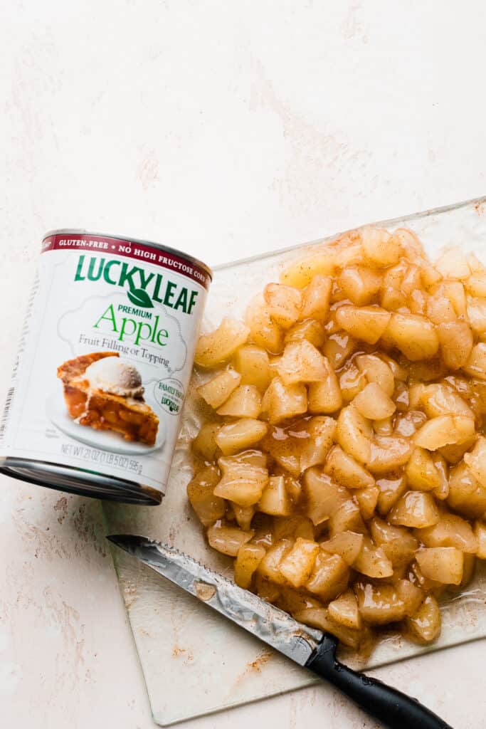 A can of Lucky Leaf Apple Fruit Filling on a cutting board with diced apple pie filling.