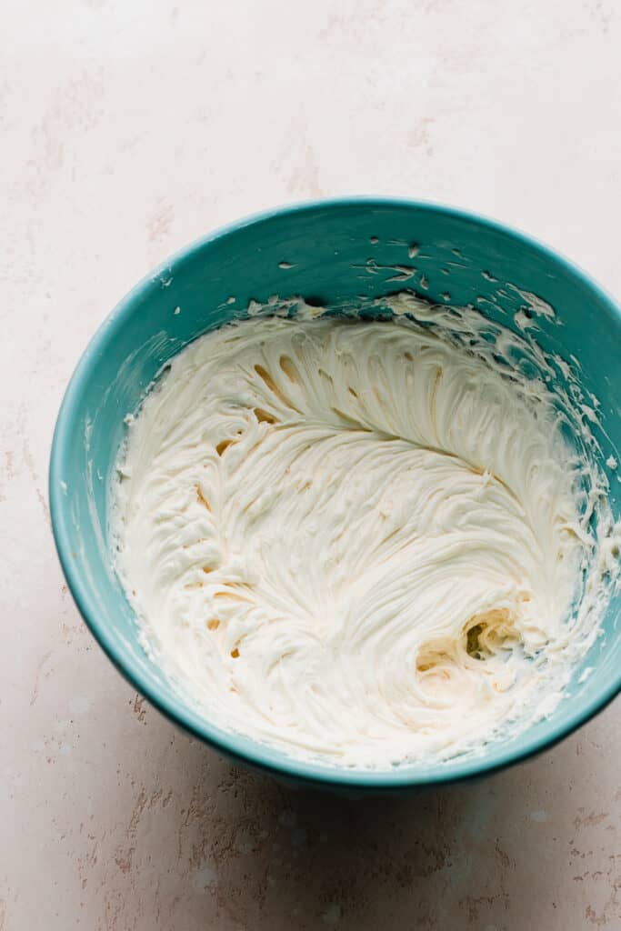 A bowl of creamed cream cheese, sugar, sour cream, and vanilla.