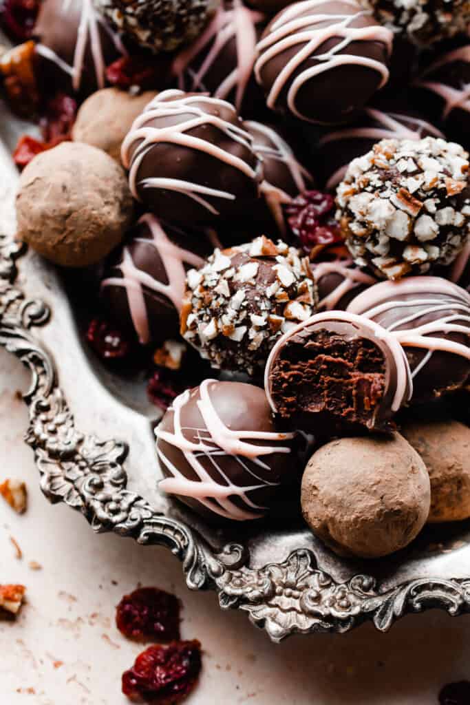 A silver platter of chocolate truffles rolled in cocoa, nuts, or decorated with chocolate.