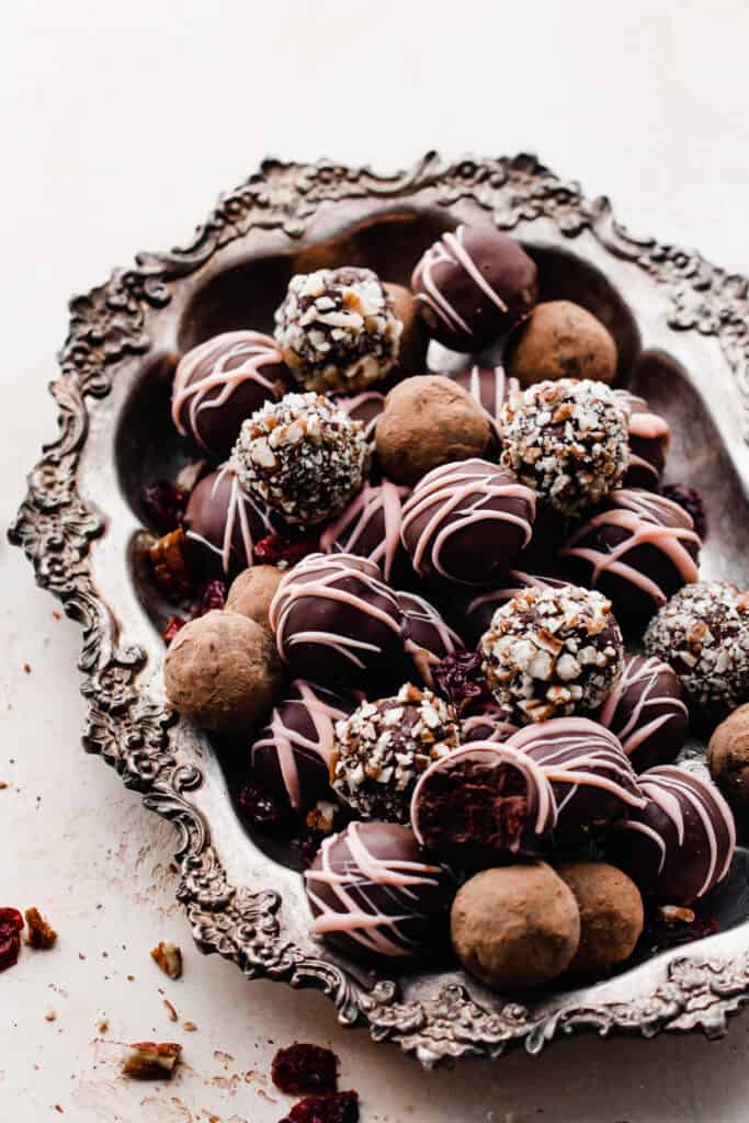 A silver tray full of chocolate truffles with different toppings.