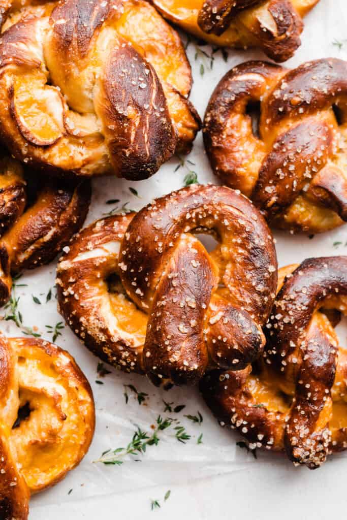 Soft pretzels with melty cheddar cheese piled on parchment paper.