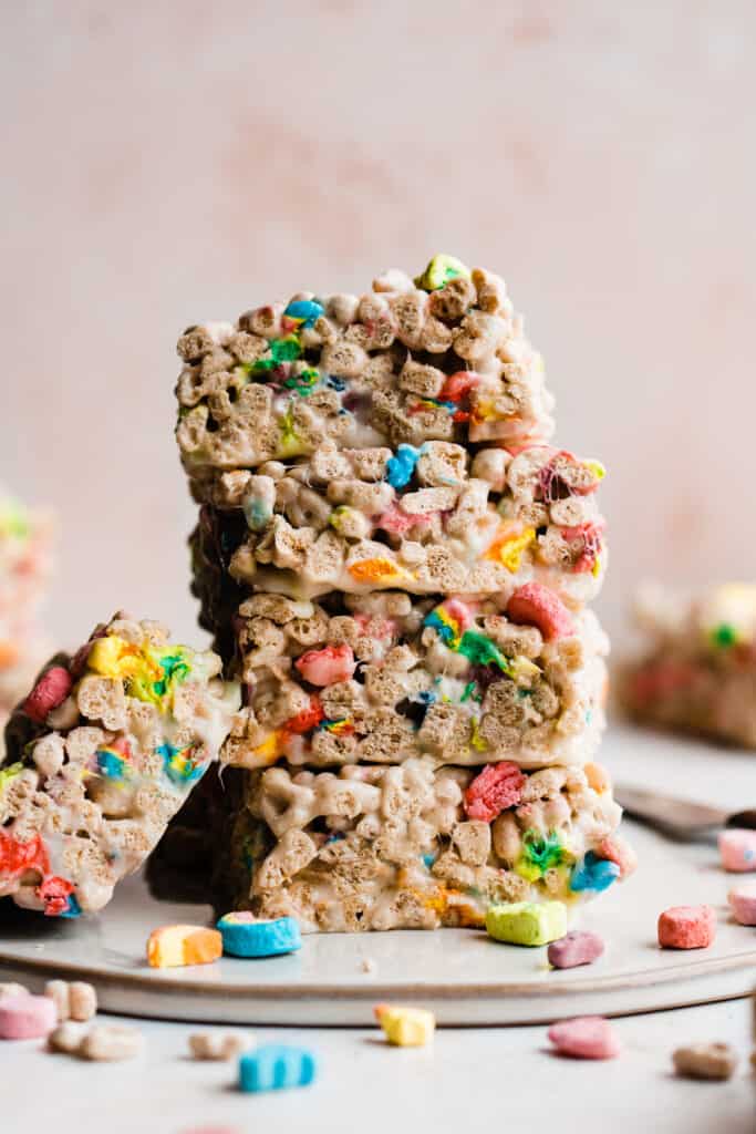 A stack of lucky charm rice krispie treats against a pink background.