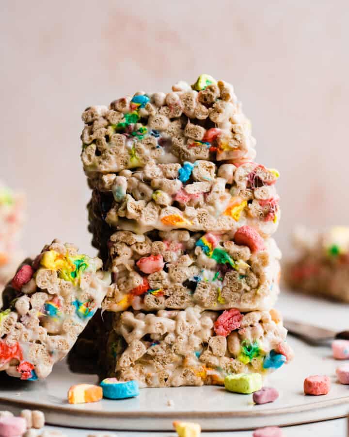 A stack of colorful rice krispie treat bars against a pink background.
