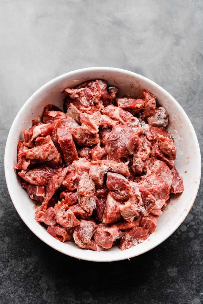 A bowl of lamb stew meat tossed with flour and spices. 