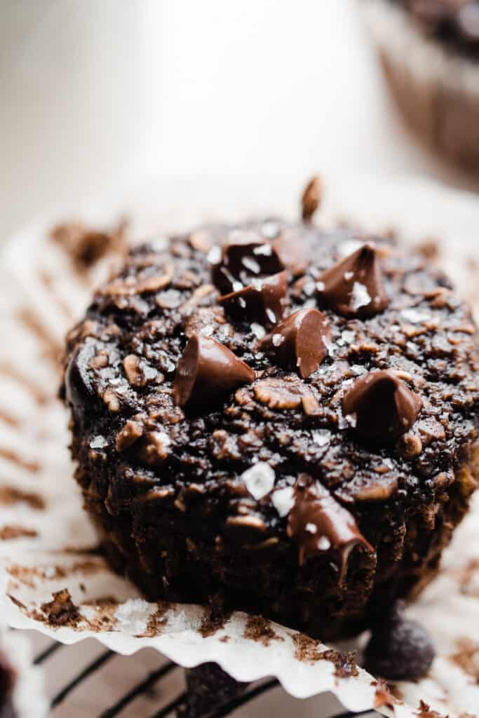 A close-up of a banana chocolate oat muffin dotted with chocoalte chips and flaky sea salt.