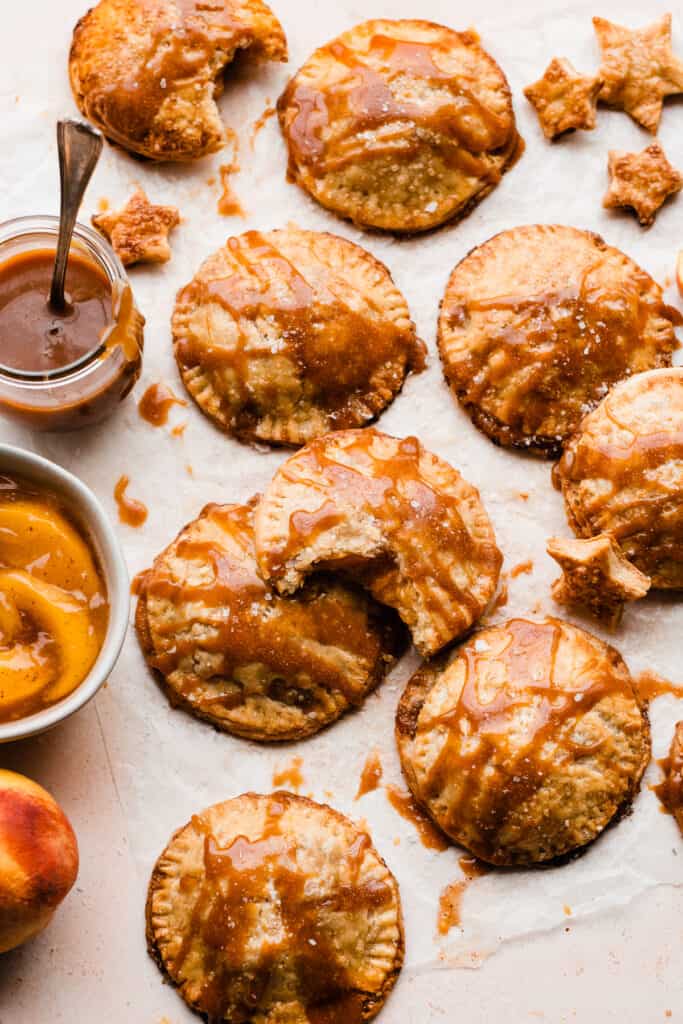 Peach Hand Pies drizzled with caramel with little pie star cutouts scattered around.