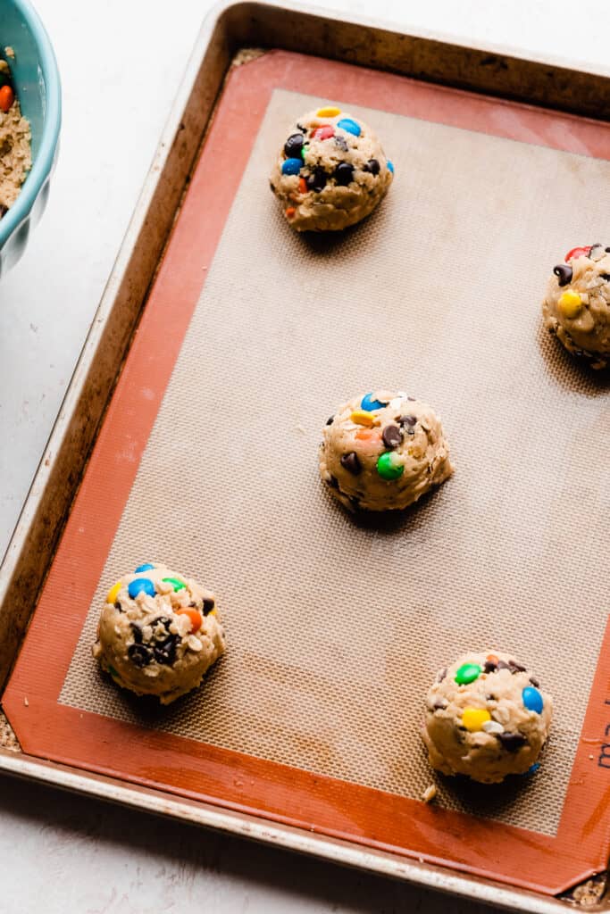 A lined baking sheet with the cookie dough balls.