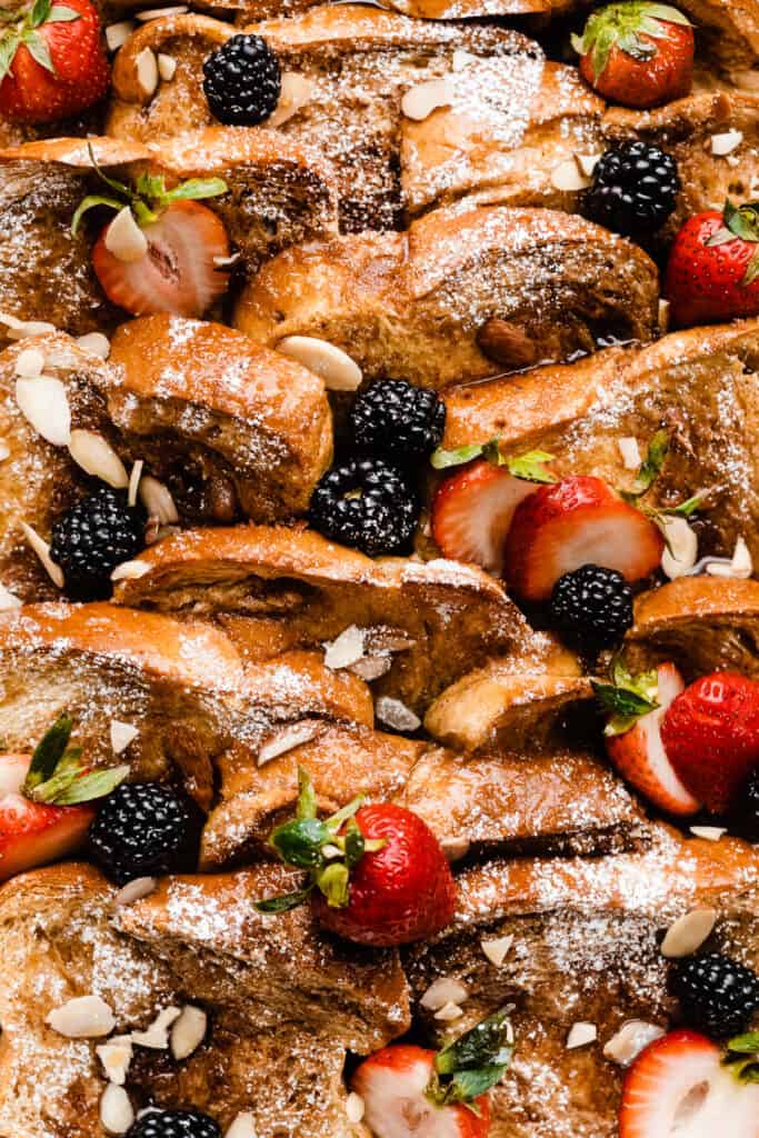 A close-up of the baked french toast with layers of brioche bread, fresh berries, and maple syrup.