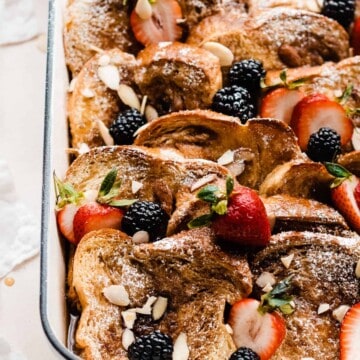 A close-up of the french toast casserole with fresh berries and maple syrup on top.