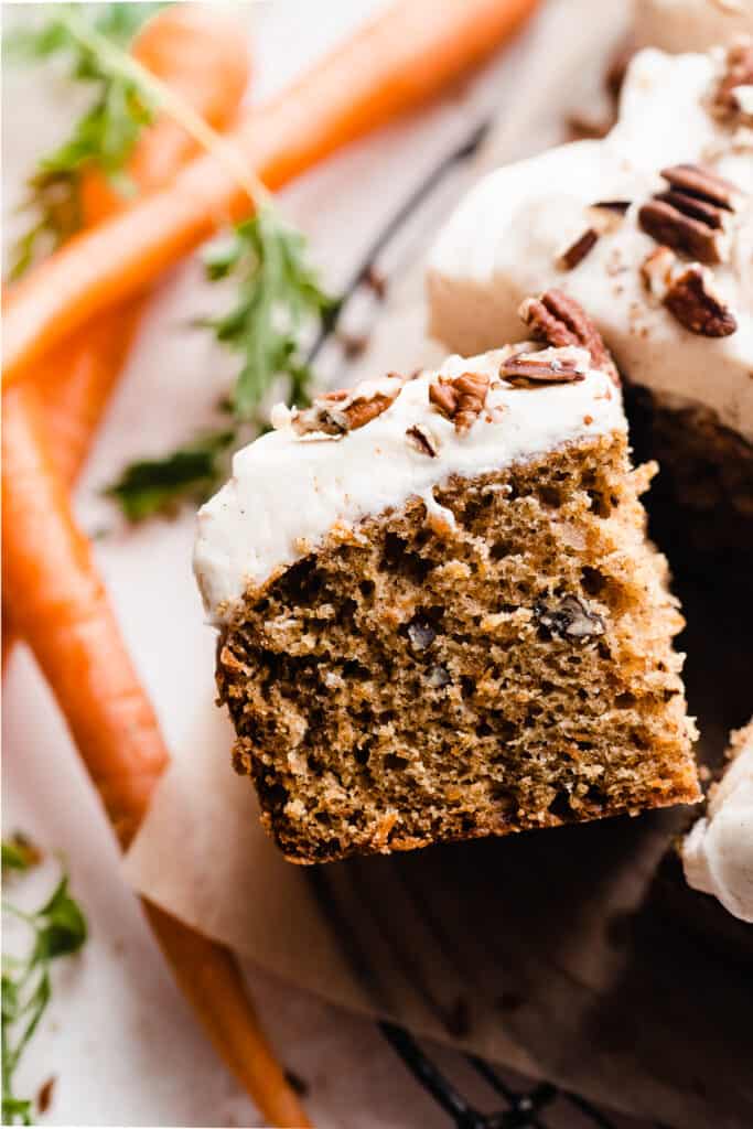 A close-up of a slice of carrot cake topped with creamy frosting.