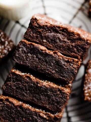 A stack of fudgy brownies with crackly tops and a dusting of powdered sugar.