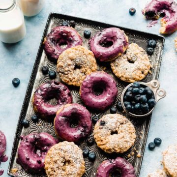 Blueberry donuts on a vintage tray with a blue backdrop.