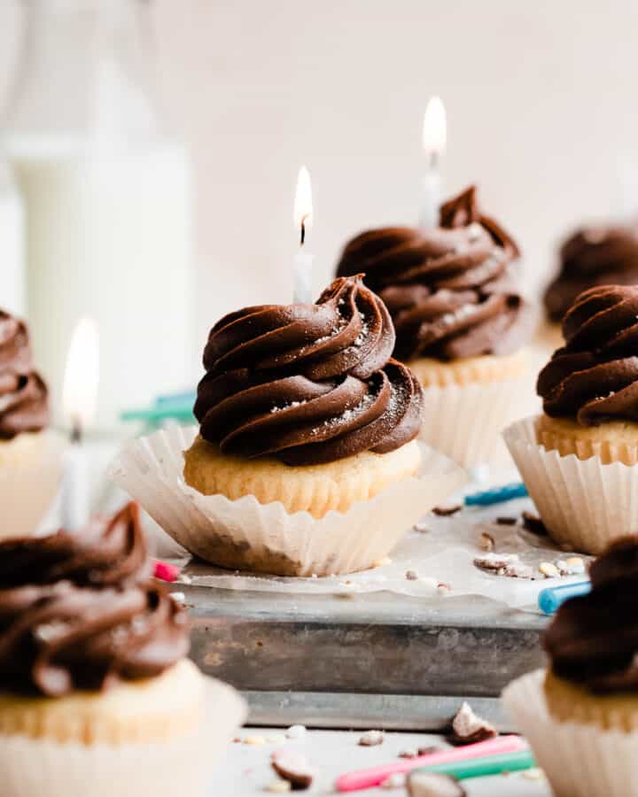 Chocolate frosted yellow cupcakes with birthday candles.