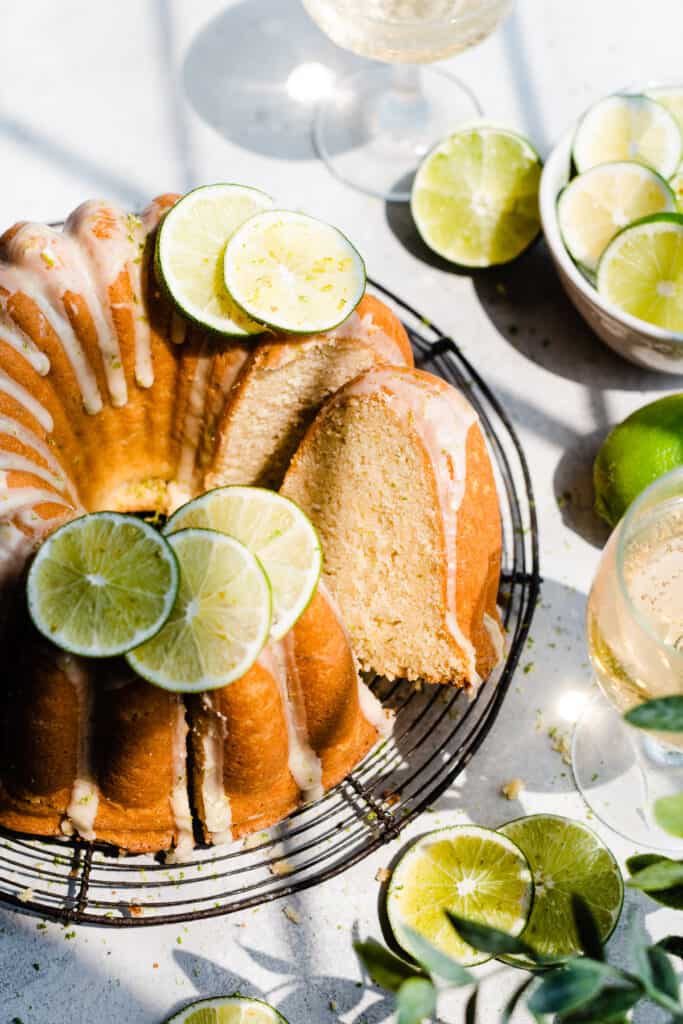 A top-down view of the sliced bundt cake, topped with lime zest, lime glaze, and lime slices.