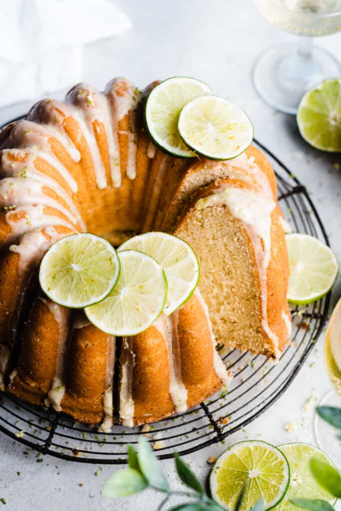 A top-down view of the glazed key lime cake topped with lime slices and lime zest.