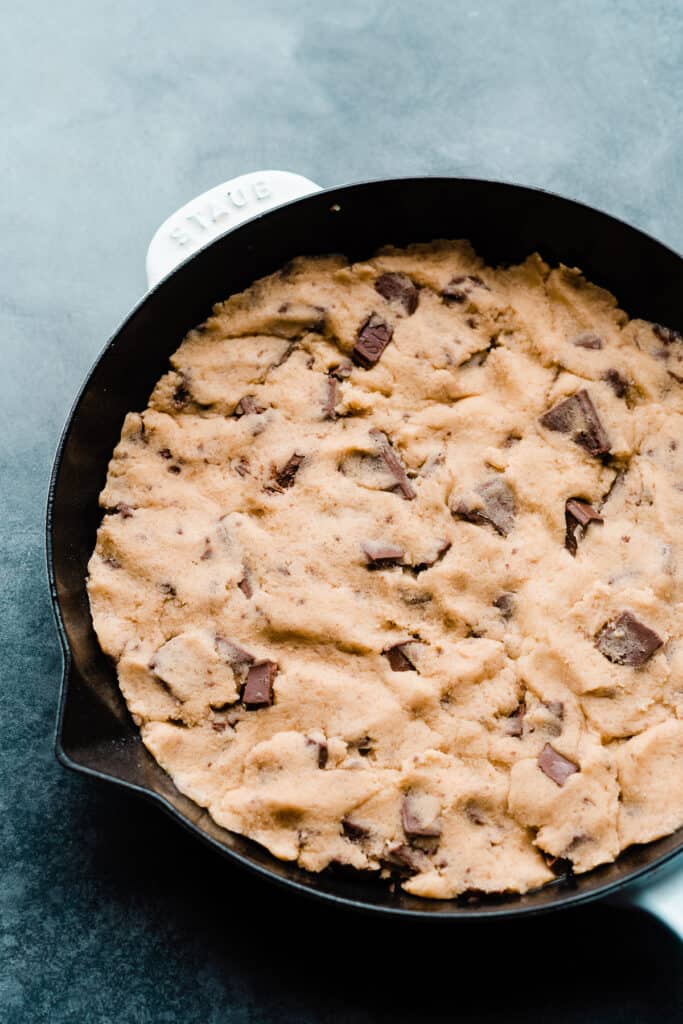 Half the cookie dough pressed into a cast iron skillet.