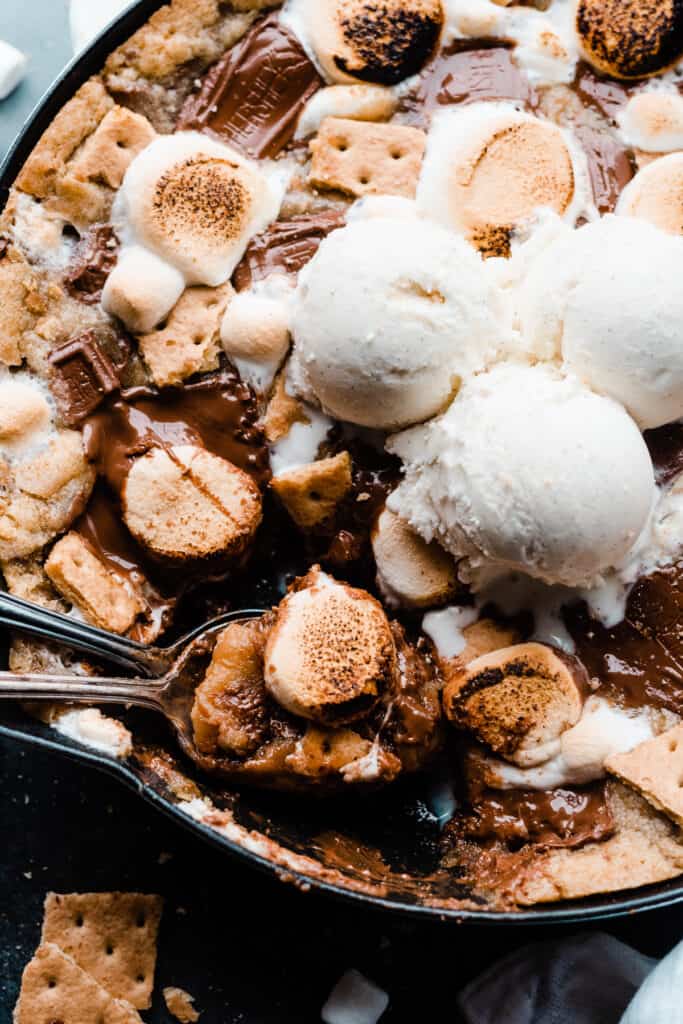 A close-up of two spoons digging into the gooey s'mores cookie.