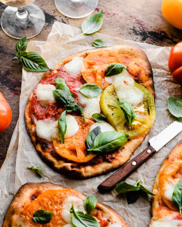 Margherita flatbread pizzas on a wooden surface.