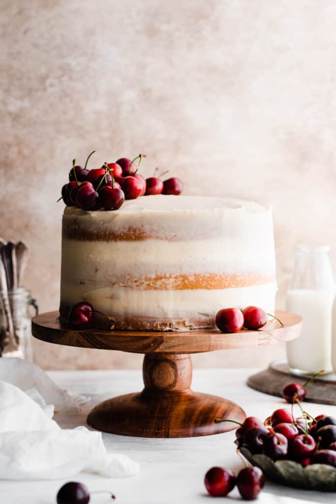 The unsliced white forest cake, topped with fresh cherries.