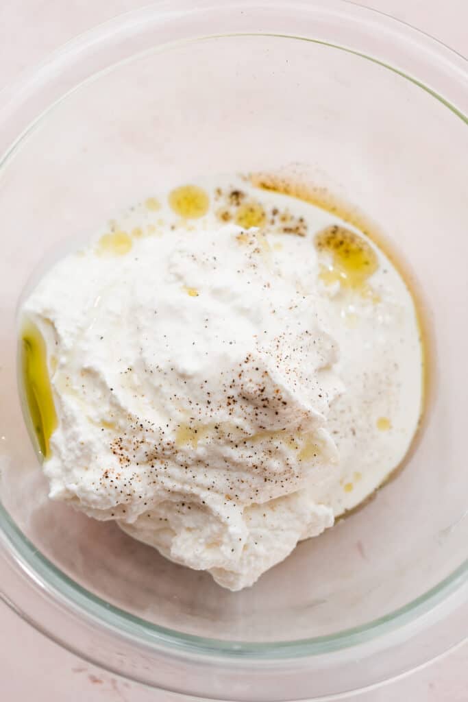 A bowl of ricotta, olive oil, heavy cream, salt, and pepper.