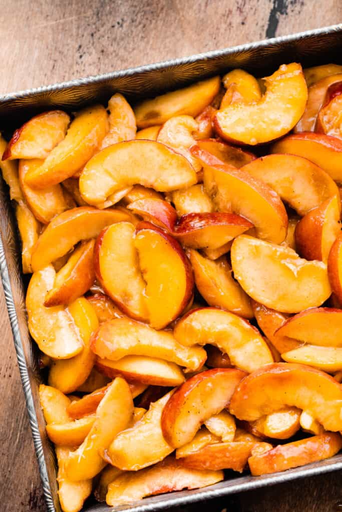 Sliced peaches in the baking dish. 