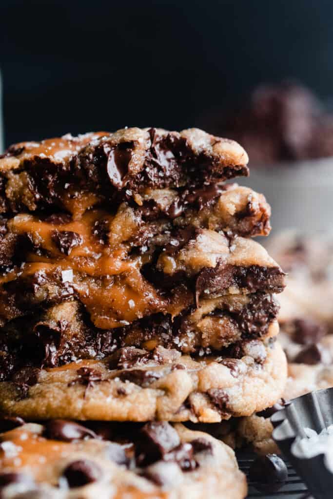 A close-up on a stack of the cookies with melty chocolate and gooey caramel dripping out.